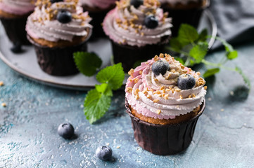 Homemade cupcakes with blueberries on dark blue concrete background.