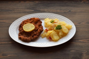 Weiner schnitzel with potato salad on a wooden background