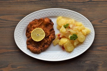 Weiner schnitzel with potato salad on a wooden background