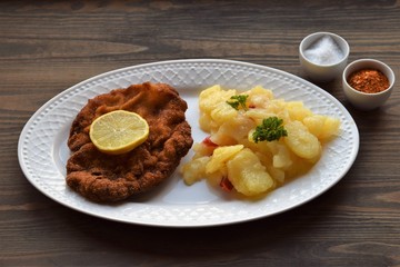 Weiner schnitzel with potato salad on a wooden background