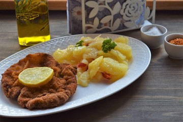 Weiner schnitzel with potato salad on a wooden background