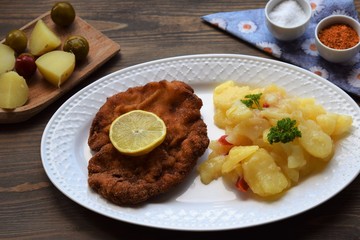 Weiner schnitzel with potato salad on a wooden background