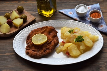 Weiner schnitzel with potato salad on a wooden background