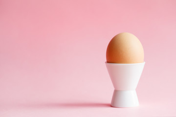 chicken egg in eggcup isolated on pastel pink background