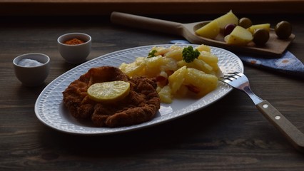 Weiner schnitzel with potato salad on a wooden background