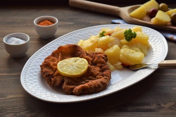 Weiner schnitzel with potato salad on a wooden background