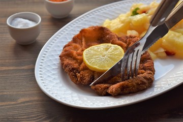Weiner schnitzel with potato salad on a wooden background