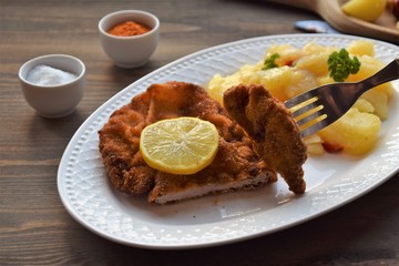 Weiner schnitzel with potato salad on a wooden background