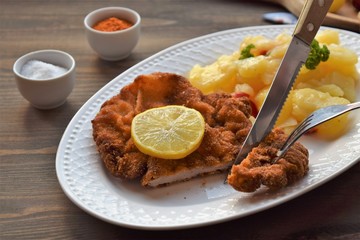 Weiner schnitzel with potato salad on a wooden background