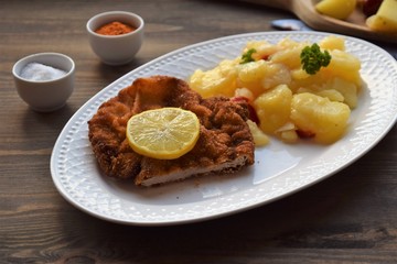 Weiner schnitzel with potato salad on a wooden background