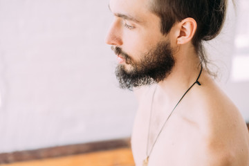 Young sporty man doing yoga in studio, with wooden floor and big windows. Freedom, health and yoga...
