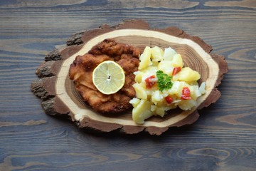 Weiner schnitzel with potato salad on a wooden background