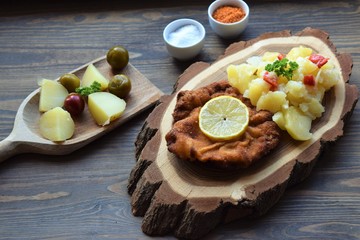 Weiner schnitzel with potato salad on a wooden background