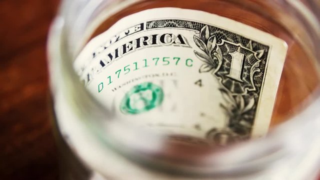 One dollar bill note in glass jar.Money savings and poverty concept
