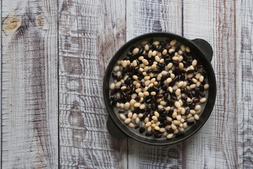 Stewed beans in a pan on a wooden table.
