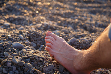 Foot close-up on a background of stones on the Black Sea, Sochi.