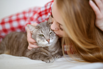 Beautiful girl with cat on bed in pajamas, toning