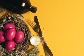 Fototapeta na wymiar easter eggs pink on yellow background with spoon and fork and dried grass with wood vine and flower and bottle