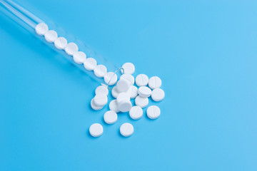 Medicine white pills in the test tube on blue background. Copy space for text