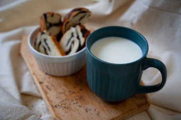 Sliced bread rolls with poppy seed filling on a wooden Board and a mug of milk