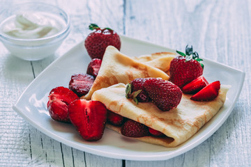 Pancakes with strawberries. On a white wooden background.