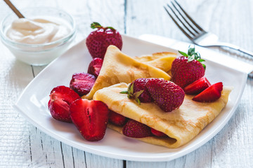 Pancakes with strawberries. On a white wooden background.
