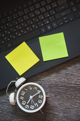 Office desk table with keyboard and alarm clock on wooden background. Top view and copy space, flat lay