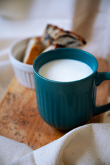 blue milk mug in the foreground and poppy seed bun in the background