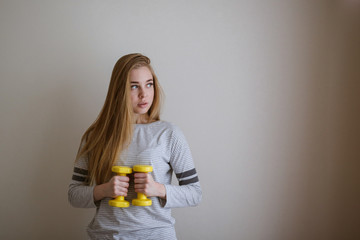 Slim blonde girl with dumbbells in hands,exercises