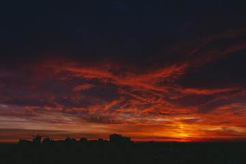 Obraz premium Fiery red blood vampire dawn. Amazing warm dramatic fire blue dark cloudy sky. Orange sunlight. Atmospheric background of sunrise in overcast weather. Hard cloudiness. Storm clouds warning. Copy space