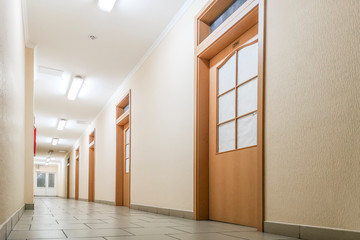 Obraz na płótnie Canvas Empty long corridor. Empty office corridor with many doors of light wood