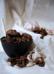 Fototapeta na wymiar dried mushrooms with garlic in a black Cup on a white linen tablecloth