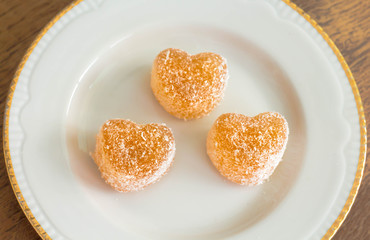 three small heart shaped candied fruit jelly sprinkled with coconut chips, healthy food, vegan