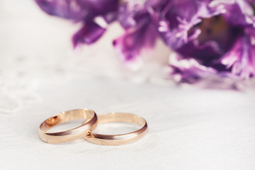 gold wedding rings on a white napkin on the background of a bouquet of  flowers