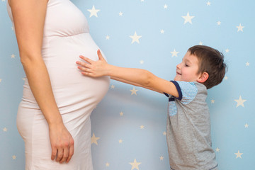 Cute child hugging belly pregnant mother. Happy kid hugging pregnant mother's belly. Pregnancy and new life concepts