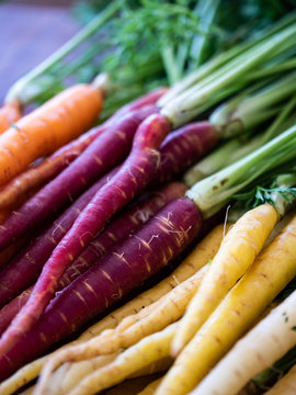 Stacked bunch of rainbow carrots in soft focus and separated by color