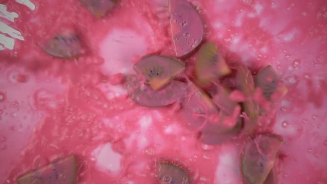 Falling paints with kiwi slices in slow motion.