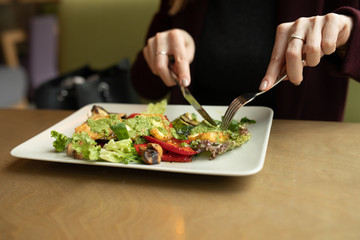 Close up attractive woman hand holding fork and spoon to eating vegetable salad at lunch in cafe 