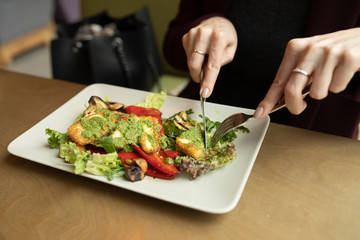 Close up attractive woman hand holding fork and spoon to eating vegetable salad at lunch in cafe 