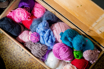 Wool in coils and balls for knitting, knitting needles.  in a large wooden chest