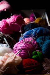 Wool in coils and balls for knitting, knitting needles.  in a large wooden chest
