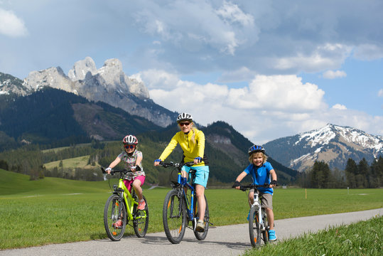 Happy Family Riding A Bike  In A Beautiful Mountain Landscape.