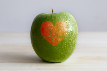 a green apple with a red heart and an electrocardiogram wave shape over