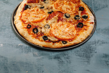 Italian pizza with tomatoes, chicken, olives on wooden background.