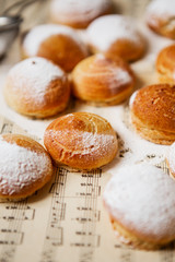 Homemade profiteroles on the music sheet with notes. Profiteroles (choux à la crème) - French choux pastry balls filled with custard or cottage cheese