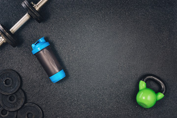 Plakat Fitness or bodybuilding concept background. Product photograph of old iron dumbbells on black grey, conrete floor in the gym. Photograph taken from above, top view with lots of copy space