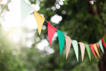 Garland of colorful flags at sunset in summer garden. Concept of celebration Happy Birthday party....