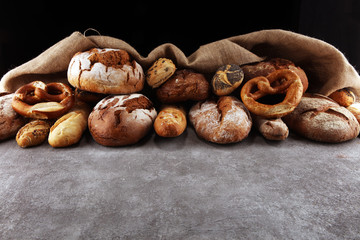 Assortment of baked bread and bread rolls on stone table background