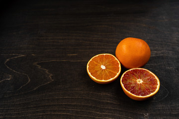 A closeup photo of vibrant organic blood oranges on a dark background with copy space.