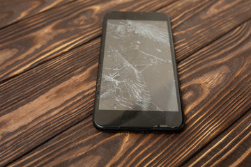 Broken mobile phone on a  wooden background. Repair of mobile phone